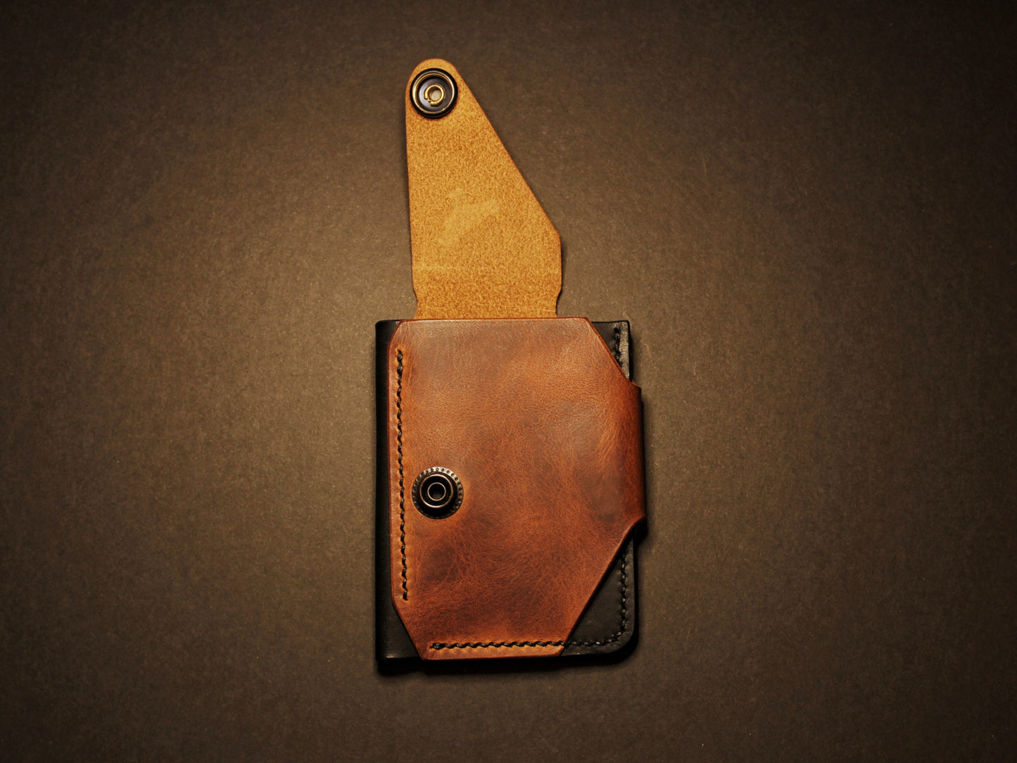 Brown leather pouch with flap on a black background