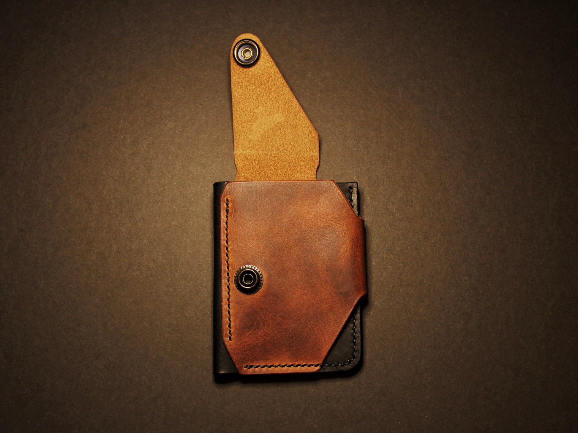 Brown leather pouch with flap on a black background