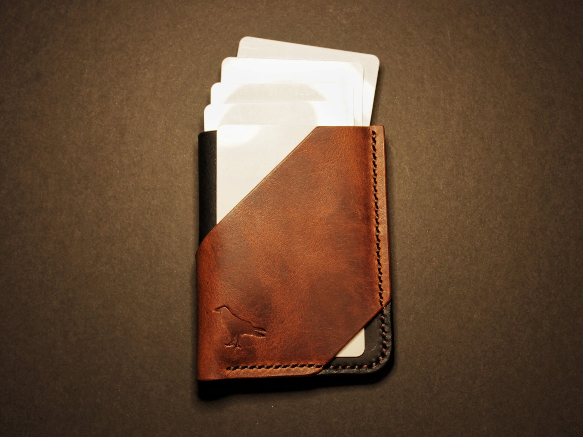 Brown leather wallet with cards on a dark brown background