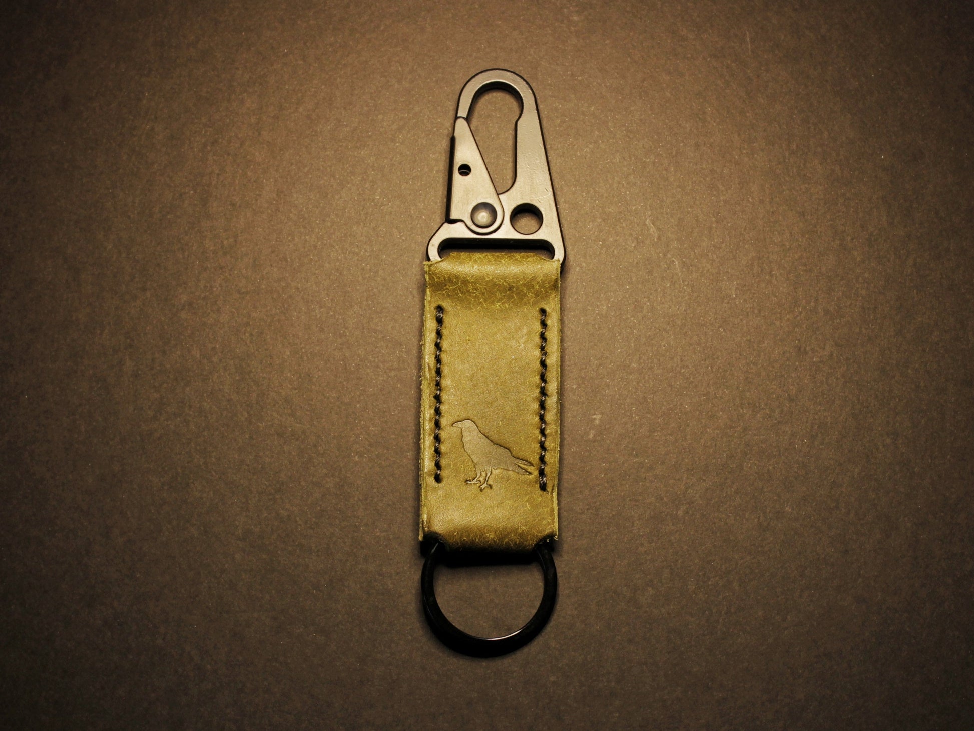 Green leather keychain with metal clip on a dark brown background