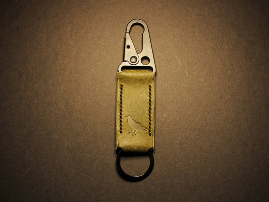 Green leather keychain with metal clip on a dark brown background