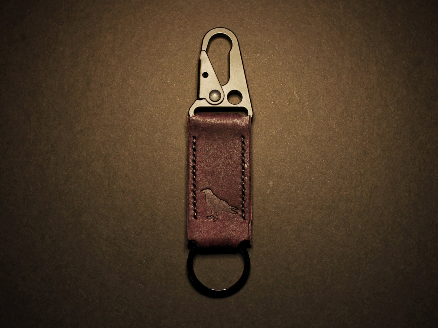 Purple leather keychain with metal clip on a dark brown background